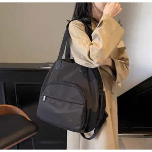 Vista dettagliata di uno zaino da viaggio in nylon nero versatile con tasca frontale e spallacci.