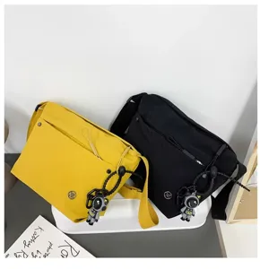 Detailed view of casual nylon crossbody bag in yellow and black, featuring astronaut charm.
