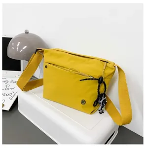 Yellow nylon crossbody bag for women, lightweight casual shoulder bag with wide strap and cute charm.