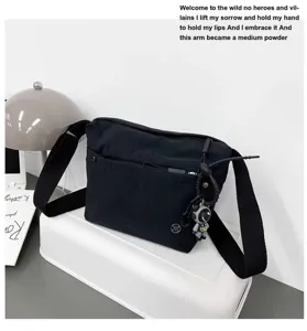 Detail view of black nylon crossbody bag with zipper pocket, wide strap and cute astronaut charm.
