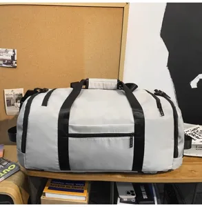 Vista dettagliata di una borsa da viaggio grigia chiara capiente con cinghie nere sul ripiano.