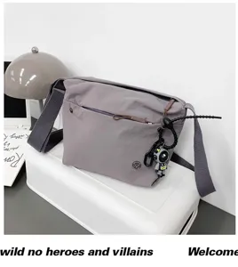 Detailed view of grey nylon crossbody bag featuring front zip pocket and cute astronaut pendant.