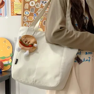 Detail shot of a minimalist white canvas tote bag with large capacity and cute burger charm.