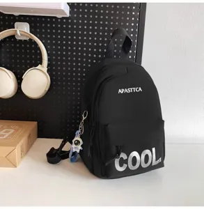 Close-up of black mini backpack detail, featuring front pocket, zipper and cool keychain.