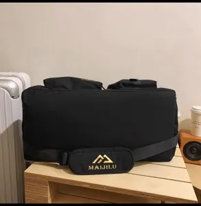 Detailaufnahme der schwarzen Reisetasche mit Riemenlogo und geräumigem Stauraum.