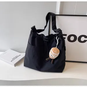 Vista detallada de bolso tote negro casual con cordón y bonito colgante de peluche.