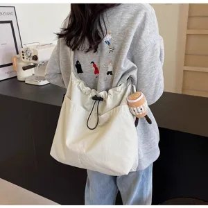 Vista detallada del bolso tote de lona informal con cordón y bonito colgante de felpa.