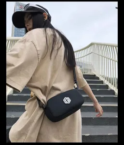Detail shot of black waterproof crossbody phone bag worn by model on outdoor urban stairs.