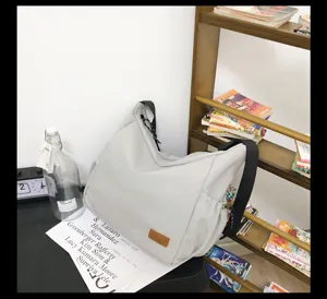 Detailed view of the light grey canvas crossbody bag showing durable fabric and black strap.