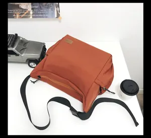 Canvas crossbody bag detail showing durable brown fabric, front zipper pocket and strap.