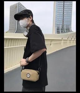 Detailed shot of streetwear crossbody phone bag worn by model outdoors with modern urban view.