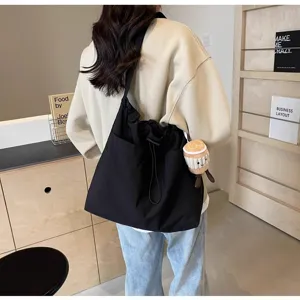 Vista detallada del bolso tote casual de lona negra, mostrando gran capacidad y estilo de hombro.