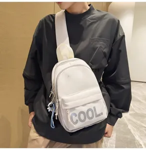 Detailed close-up view of white chest bag with cool text print and wide strap for daily wear.