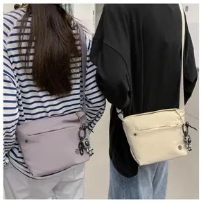 Nylon crossbody bag for women, lightweight casual shoulder bag with pendant detail.