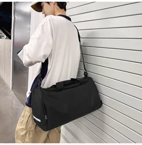 Vue latérale détaillée du sac de sport noir avec bandoulière porté par un mannequin.