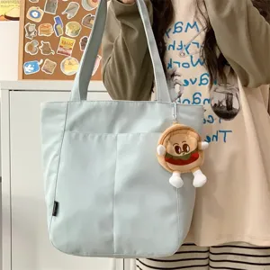 Casual large capacity canvas tote bag for women, simple shoulder bag with cute plush pendant.