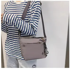 Detailed view of the lightweight nylon crossbody bag featuring secure zip pocket and charm.