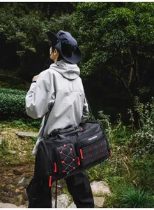 Outdoor travel duffel bag detail view showcasing durable black fabric and red straps.