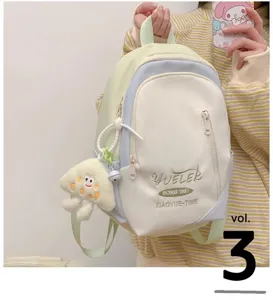 Detail view of a cute pastel color blocking backpack with a plush pendant for daily use.
