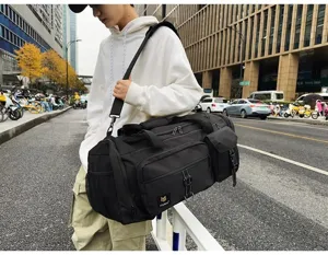 Detailansicht einer großen schwarzen Reisetasche mit Schultergurt im Außeneinsatz.