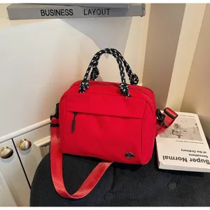 Borsa a tracolla rossa in nylon con manici in corda e tasca frontale per i dettagli del prodotto.