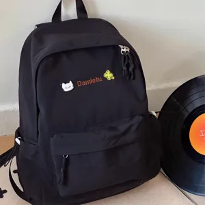 Detailed view of the cute black Japanese casual backpack with embroidered cat design and front pocket.
