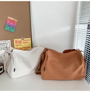 Detail view of large capacity casual crossbody bag and travel duffel in white and brown.