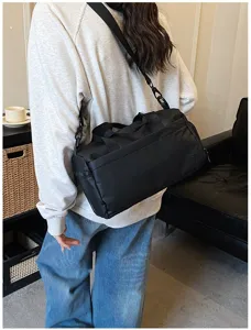 Detail shot of a black portable sports fitness bag worn cross-body, ideal for daily travel use.