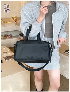 Detailed view of black travel duffel bag in casual café scene, showing handle and strap.