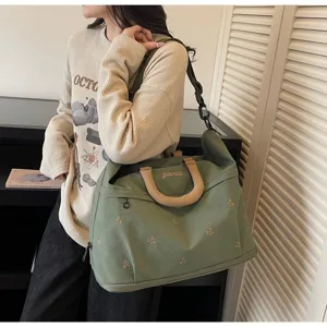 Detail view of large capacity expandable travel duffel bag with bow embroidery and handles.