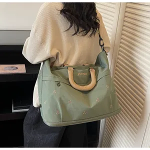 Detail shot showing cute bow embroidery, comfortable handle and spacious travel duffel bag.