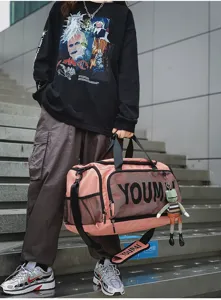 Detail view of pink gym duffel bag with mesh pocket, shoulder strap and frog keychain.