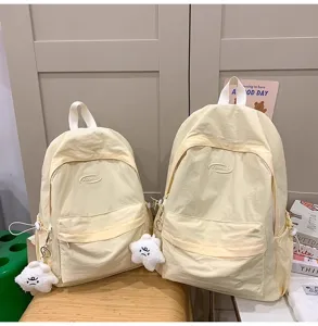 Detailed view of casual minimalist light yellow backpacks with cute plush star pendants.