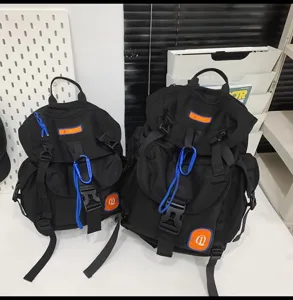 Grand sac à dos de style camping noir avec étiquette orange et mousqueton bleu pour voyage.