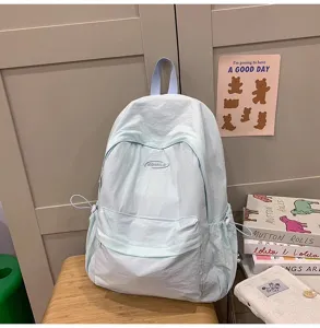 Lightweight casual solid color backpack detail showing light blue fabric and side pockets.