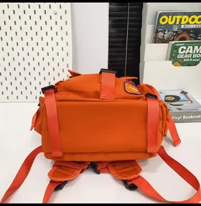 Détail de sac à dos de camping orange montrant les sangles inférieures et le tissu en nylon.