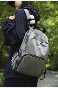 Lightweight waterproof grey checkered outdoor backpack detail shot with panda doll charm.
