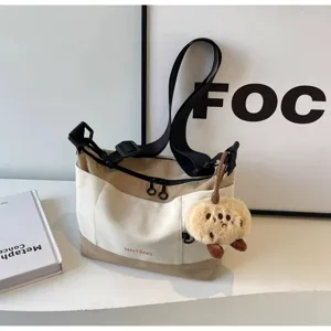 Canvas crossbody messenger bag for women, retro casual shoulder bag with cute plush pendant.