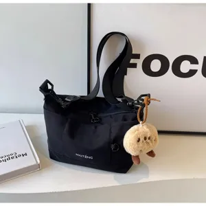 Black canvas shoulder bag for women, casual crossbody messenger bag with cute plush pendant.