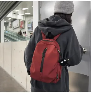 Close-up of lightweight red casual backpack with cute plush charm for daily travel and school.