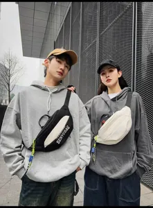 Streetwear chest bag detail shot showing stylish canvas crossbody fanny pack worn by models.