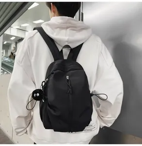 Detail shot of black lightweight casual backpack with zipper pocket and cute pendant accessory.