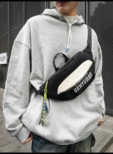 Detailed view of the stylish black and white streetwear chest bag worn by the male model.