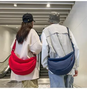 Detailed shot of couple carrying large canvas crescent dumpling crossbody bags in casual daily life style.