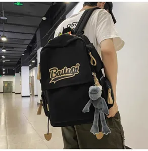 Black canvas backpack for students, large capacity casual daypack with cute plush frog pendant.