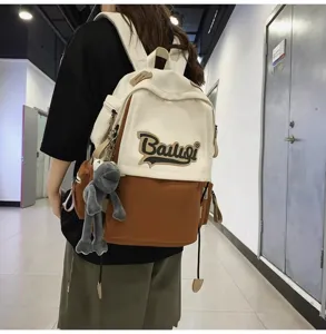Close-up detail of the dual-tone canvas backpack worn by model, featuring cute plush toy.