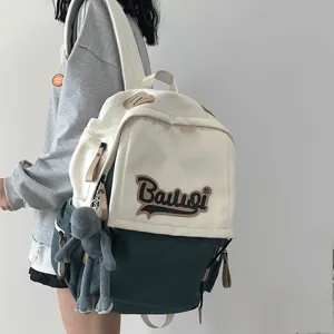 Canvas backpack for women, casual college style school bag with color block and cute doll pendant.