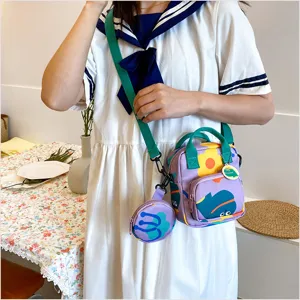 Canvas crossbody bag detail showing vibrant floral print, green straps, and cute round coin pouch.