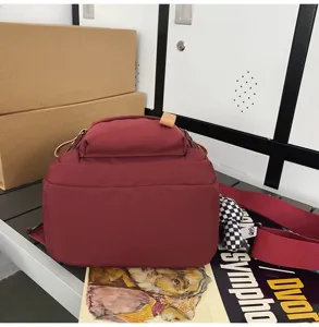 Close-up detail of the maroon canvas functional chest bag, showing durable fabric and strap.