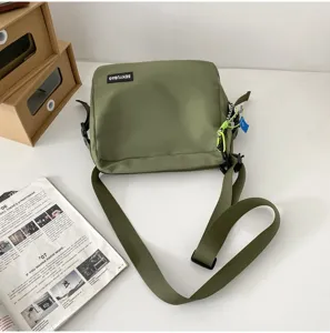 Green canvas crossbody bag detail, casual messenger bag strap and brand label view.